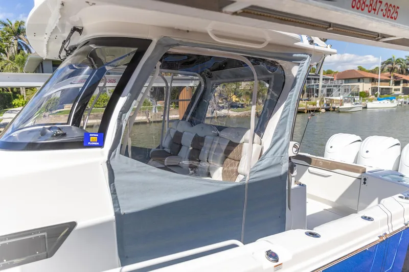 Slide: The Image of 2023 Edgewater 370CC boat with enclosed seating area, docked by waterfront homes. - 4