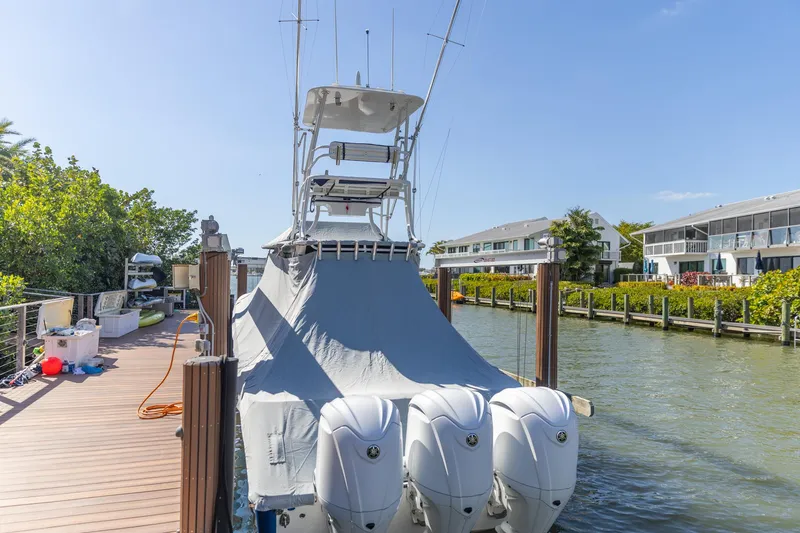 Slide: The Image of 2023 Edgewater 370CC boat docked with cover, featuring triple outboard engines. - 40