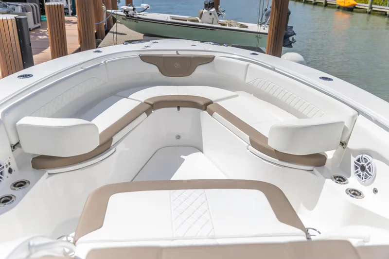 Slide: The Image of 2023 Edgewater 370CC boat interior with white and beige seating, docked by the water. - 5