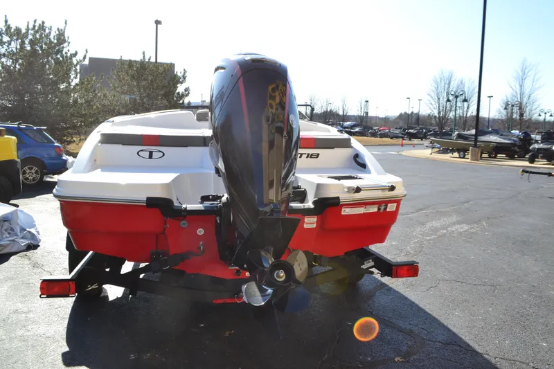 Slide: The Image of 2025 Tahoe T18 boat, red and white, parked outdoors with outboard motor. - 1