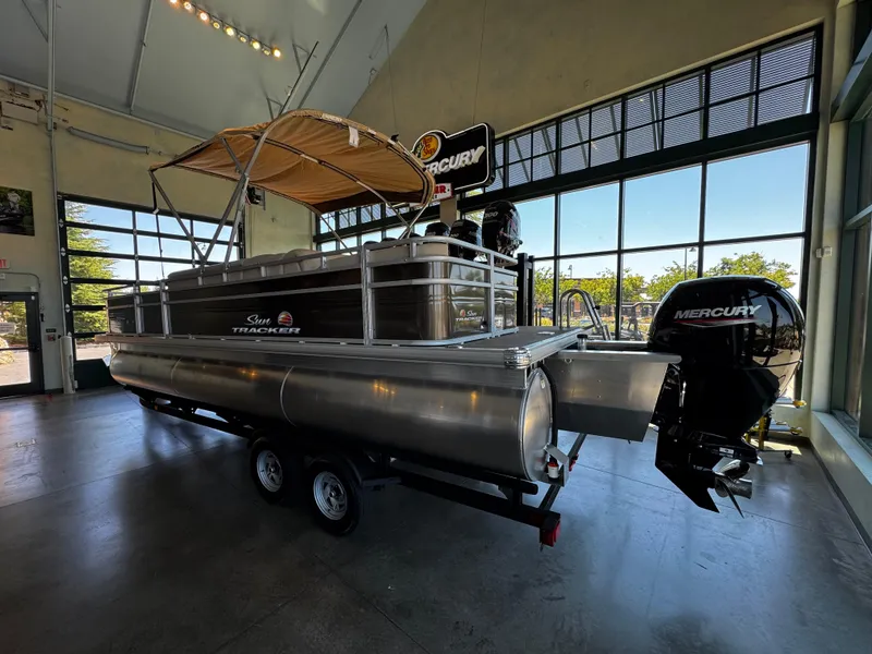 Slide: The Image of 2025 Sun Tracker Sportfish 24 XP3 pontoon boat with Mercury engine in showroom. - 2