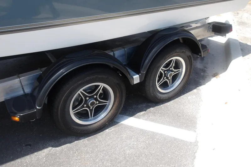 Slide: The Image of Trailer wheels of a 2025 Mako 214 Center Console boat parked on pavement. - 18