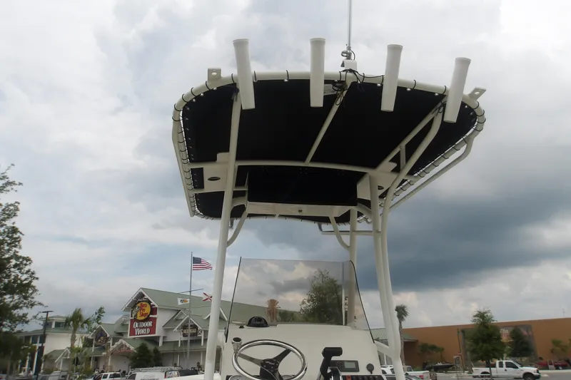 Slide: The Image of 2025 Mako 214 Center Console boat with T-top and rod holders, cloudy sky background. - 14