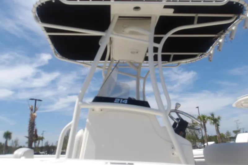 Slide: The Image of 2025 Mako 214 Center Console boat with T-top under a clear blue sky. - 17