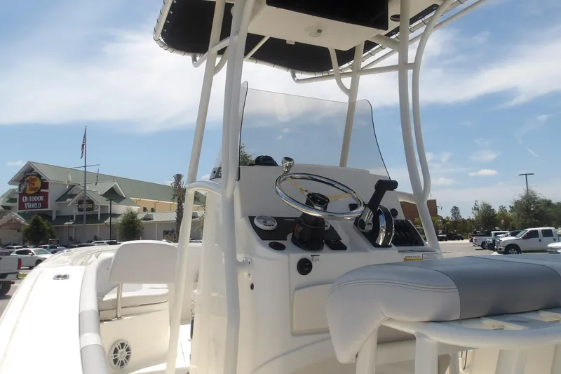 Slide: The Image of 2025 Mako 214 Center Console boat interior with steering wheel and seating, parked outdoors. - 21