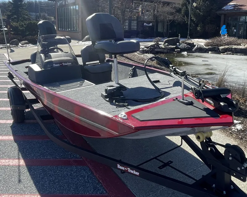 Slide: The Image of 2025 Tracker Bass Tracker Classic XL boat, red and gray, parked outdoors. - 2