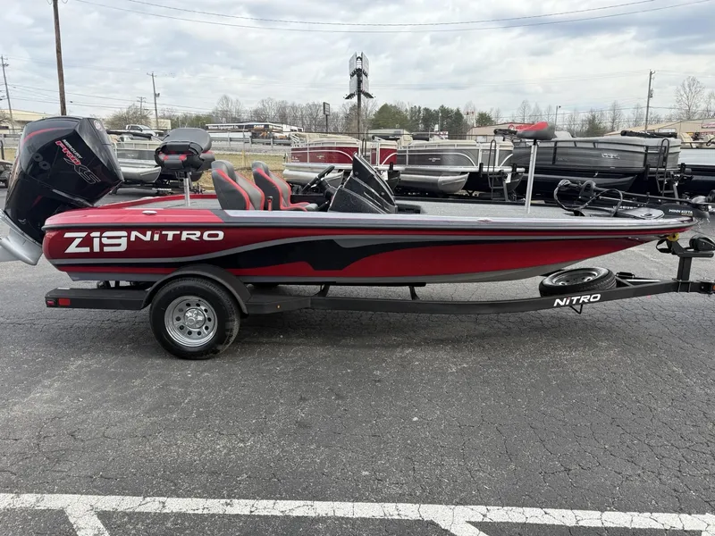 Slide: The Image of 2025 Nitro Z19 boat, red and black, parked on a trailer in a lot. - 2