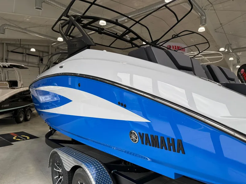 Slide: The Image of 2025 Yamaha Boats 255XD in showroom, blue and white design, on trailer. - 1