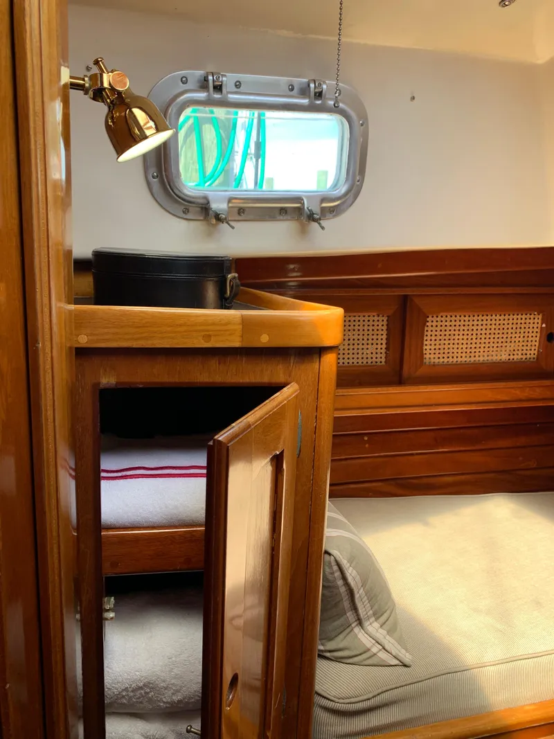 Slide: The Image of Interior of 1981 Bristol 40 Sloop, featuring wooden cabinetry and cozy sleeping area. - 12