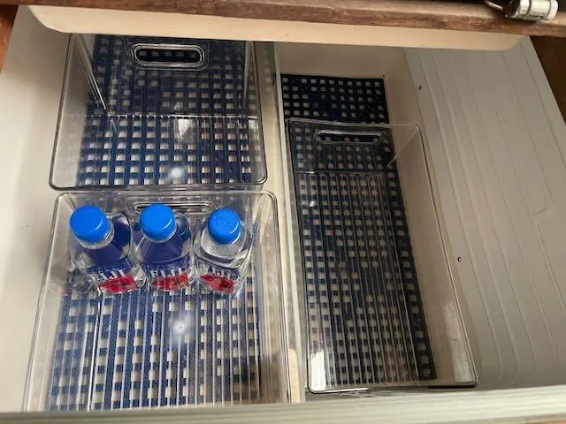 Slide: The Image of Storage compartment with water bottles on a 1981 Bristol 40 sloop, featuring checkered liners. - 18