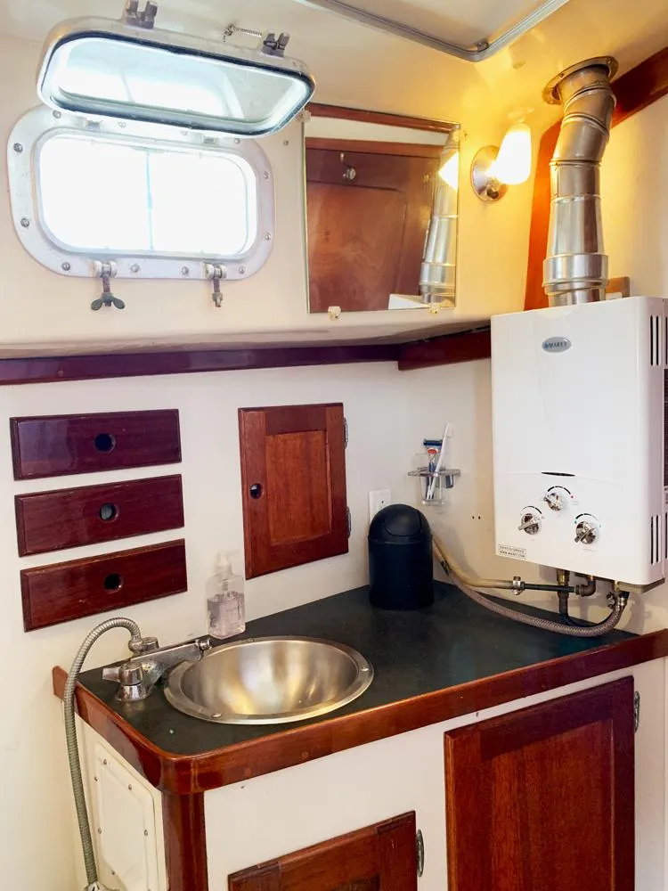 Slide: The Image of 1981 Bristol 40 Sloop interior with sink, wooden cabinets, and porthole window. - 20