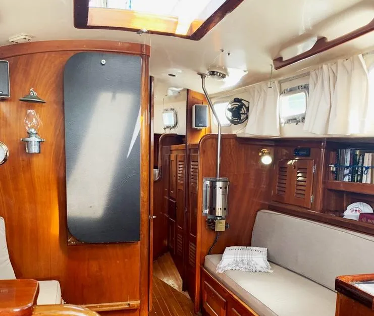 Slide: The Image of Interior of a 1981 Bristol 40 sloop, featuring wood paneling and cozy seating. - 6