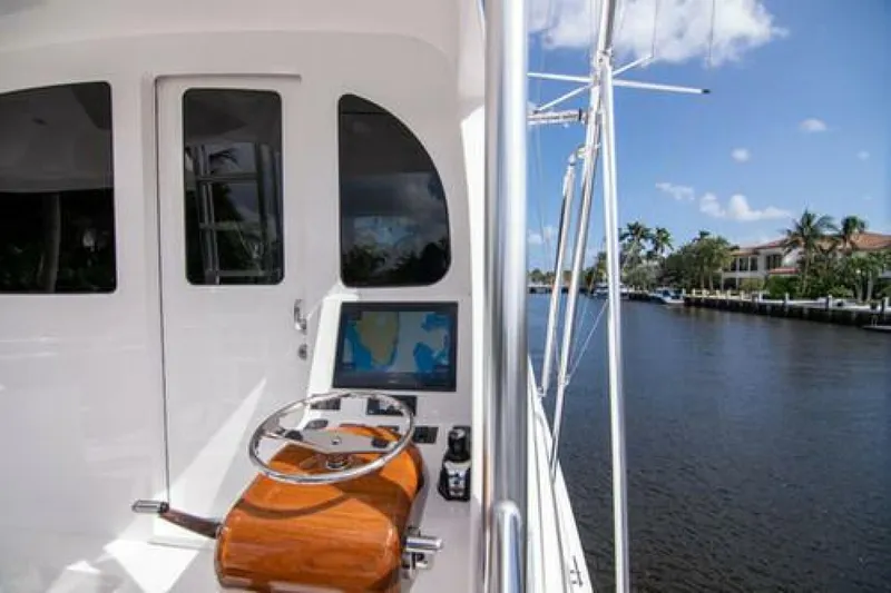 Slide: The Image of 2024 Viking 68 Enclosed Bridge yacht helm with navigation screen, docked by a scenic waterway. - 17