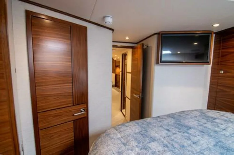 Slide: The Image of 2024 Viking 68 Enclosed Bridge cabin interior with wood paneling and mounted TV. - 20