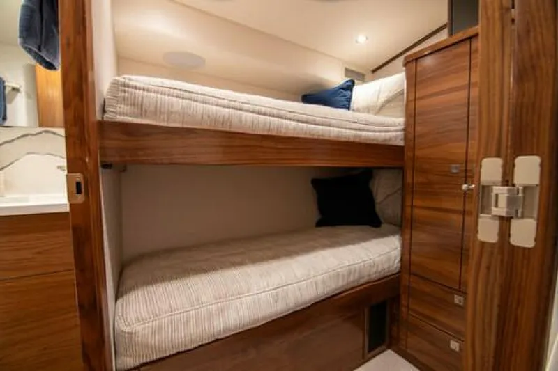 Slide: The Image of 2024 Viking 68 Enclosed Bridge cabin with wooden bunk beds and cozy lighting. - 22