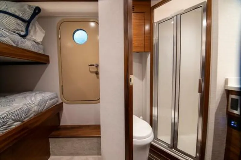 Slide: The Image of 2024 Viking 68 Enclosed Bridge interior with bunk beds and bathroom. - 27