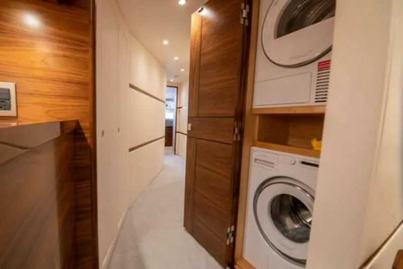 Slide: The Image of Laundry area inside 2024 Viking 68 Enclosed Bridge yacht, featuring modern appliances and wood paneling. - 28