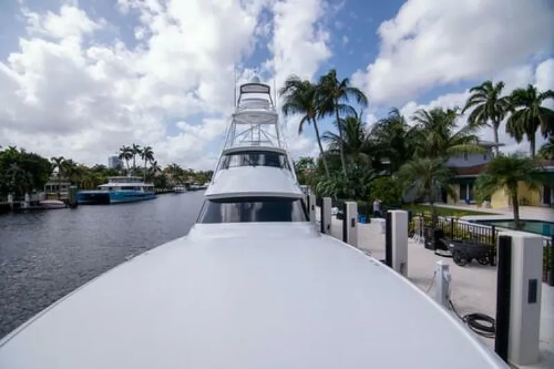 Slide: The Image of 2024 Viking 68 Enclosed Bridge yacht docked by palm trees and waterway. - 33