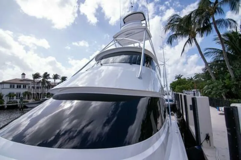 Slide: The Image of 2024 Viking 68 Enclosed Bridge yacht docked, with palm trees and cloudy sky in the background. - 34