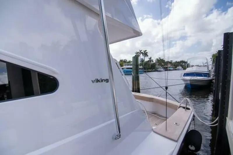 Slide: The Image of 2024 Viking 68 Enclosed Bridge yacht docked by a scenic waterfront. - 37
