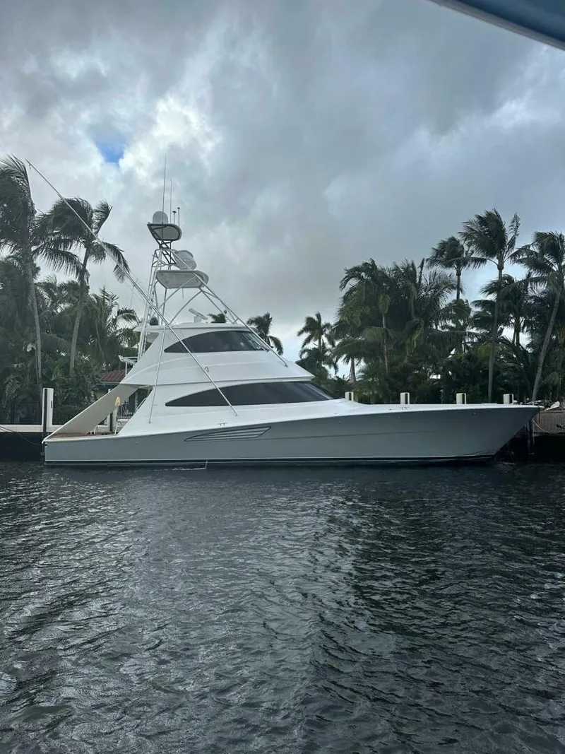 Slide: The Image of 2024 Viking 68 Enclosed Bridge yacht docked near palm trees under cloudy skies. - 41