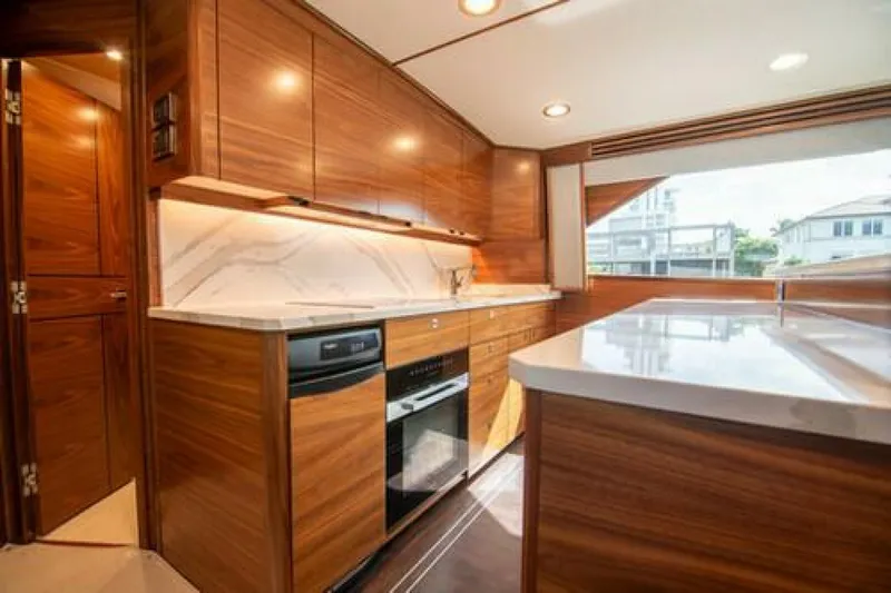 Slide: The Image of Luxurious kitchen interior of 2024 Viking 68 Enclosed Bridge yacht with modern wood cabinetry. - 8