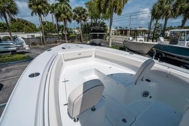 Slide: The Image of 2025 Sea Hunt Gamefish 25 boat interior with seating, parked outdoors under palm trees. - 28