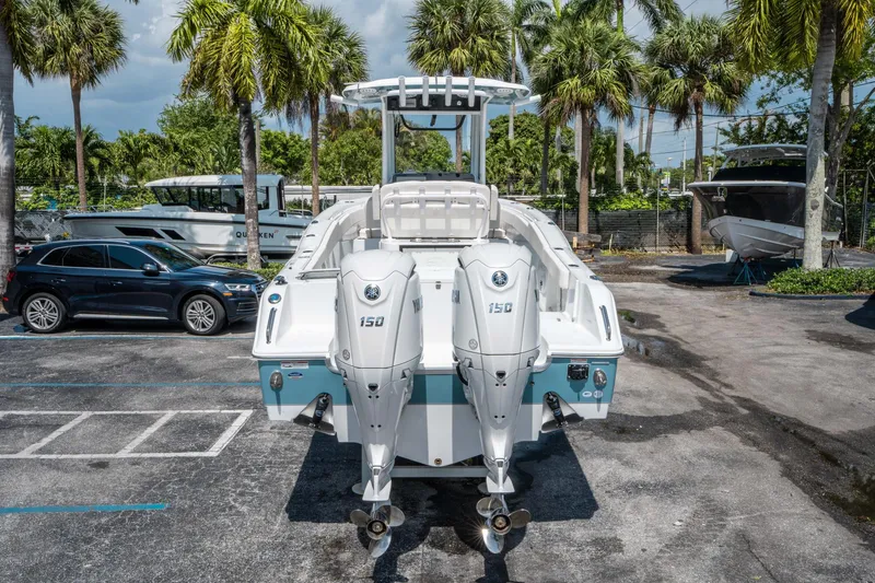 Slide: The Image of 2025 Sea Hunt Gamefish 25 boat with dual outboard engines, parked near palm trees. - 3