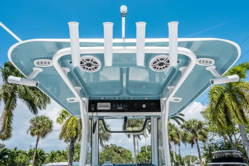 Slide: The Image of 2025 Sea Hunt Gamefish 25 boat top view with rod holders and speakers, set against a tropical backdrop. - 16