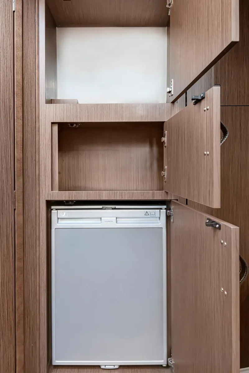 Slide: The Image of 2025 Beneteau 32 Gran Turismo interior storage with compact refrigerator. - 22