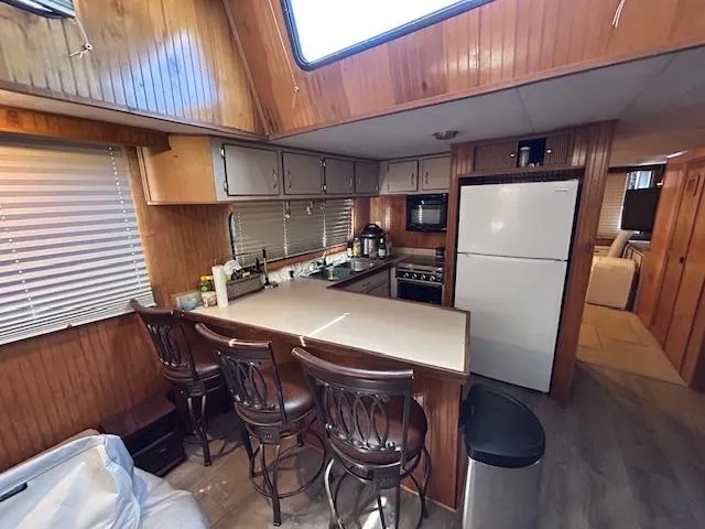 Slide: The Image of Cozy kitchen in a 1995 Gibson 5500 SERIES boat with wooden cabinetry and bar seating. - 23