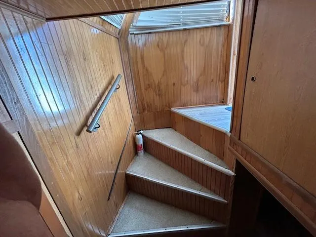 Slide: The Image of Wooden interior stairs in a 1995 Gibson 5500 SERIES boat, featuring a handrail and fire extinguisher. - 25