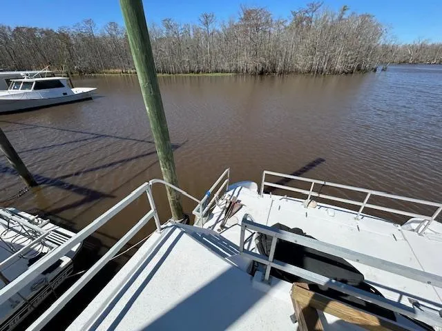Slide: The Image of Houseboat docked on a calm river, surrounded by trees, under a clear blue sky. - 42