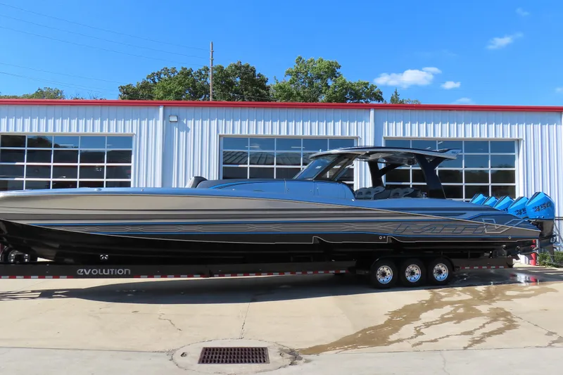 Slide: The Image of 2022 MTI 50v boat on trailer, parked outside a garage under clear blue sky. - 1