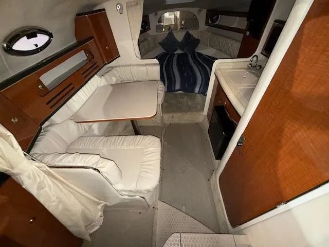 Slide: The Image of Interior of 2003 Sea Ray 280 Sundancer with seating, table, and compact kitchen area. - 11