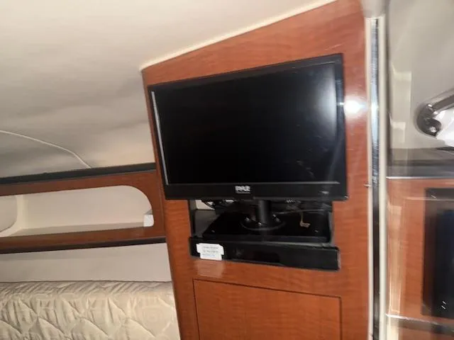 Slide: The Image of Interior of 2003 Sea Ray 280 Sundancer with mounted TV and wooden cabinetry. - 13