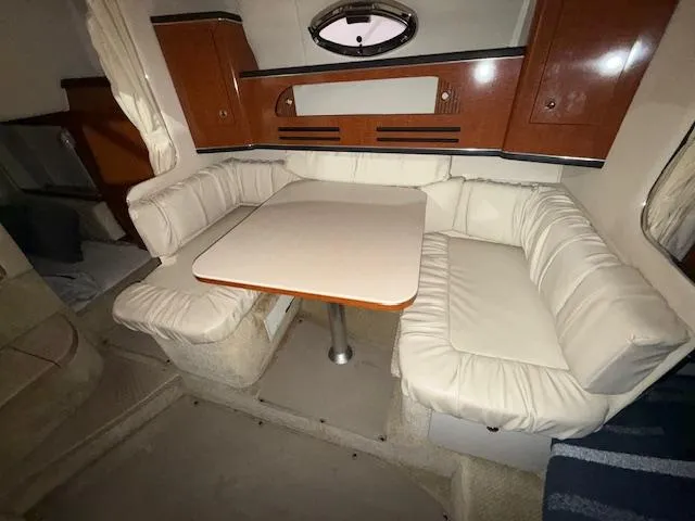 Slide: The Image of 2003 Sea Ray 280 Sundancer interior with cozy dining area and plush seating. - 14