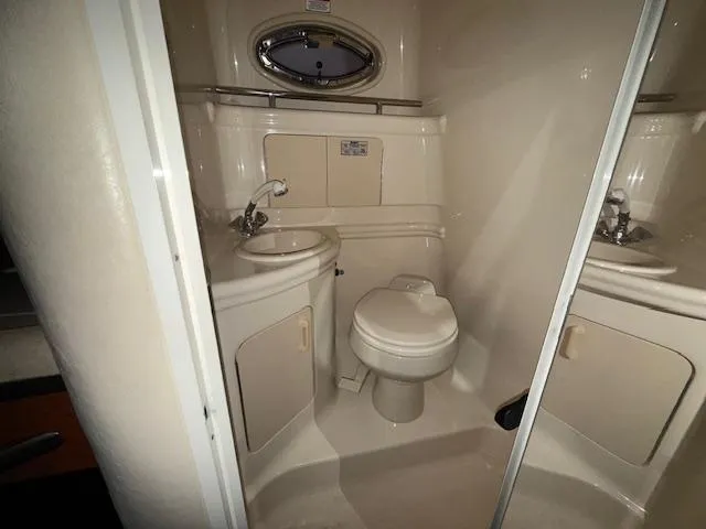 Slide: The Image of 2003 Sea Ray 280 Sundancer bathroom with sink, toilet, and porthole window. - 17