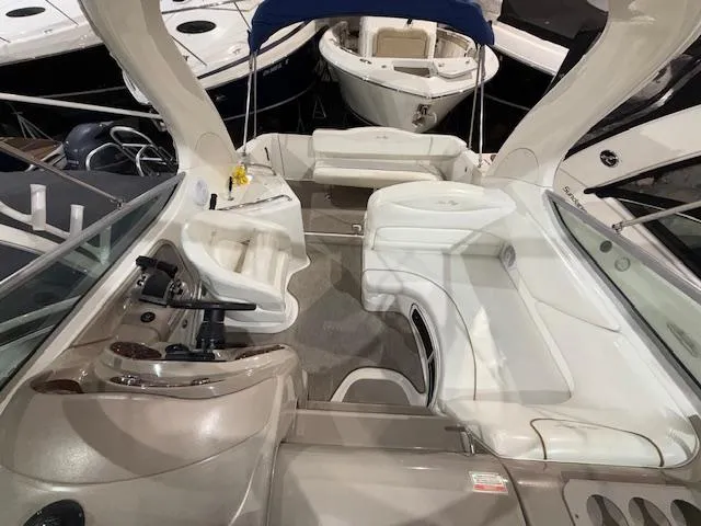 Slide: The Image of 2003 Sea Ray 280 Sundancer interior with white seating and helm, docked among other boats. - 3