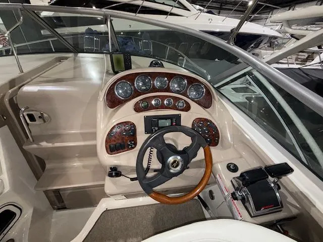 Slide: The Image of 2003 Sea Ray 280 Sundancer helm with wood-accented dashboard and steering wheel. - 9
