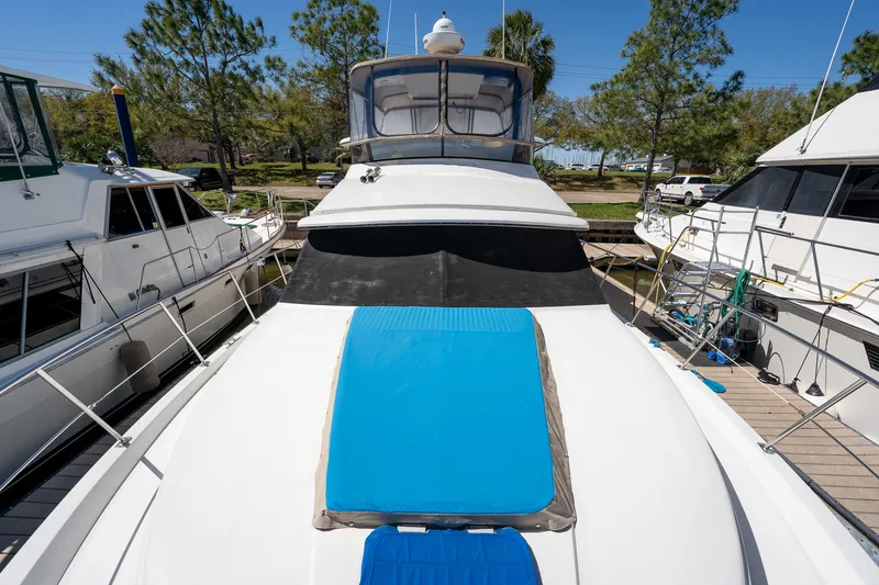 Slide: The Image of 1988 Carver 42 Aft Cabin Motoryacht docked, featuring spacious deck and blue sun pad. - 19