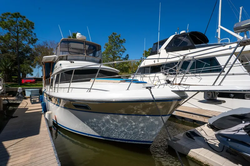 Slide: The Image of 1988 Carver 42 Aft Cabin Motoryacht docked at marina under clear blue sky. - 6