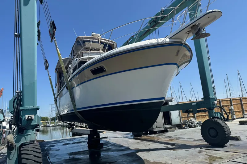 Slide: The Image of 1988 Carver 42 Aft Cabin Motor Yacht on lift at marina, clear blue sky. - 111