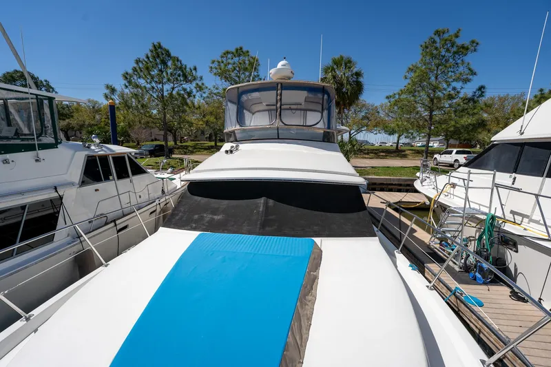 Slide: The Image of 1988 Carver 42 Aft Cabin Motoryacht docked, surrounded by trees and other boats. - 21