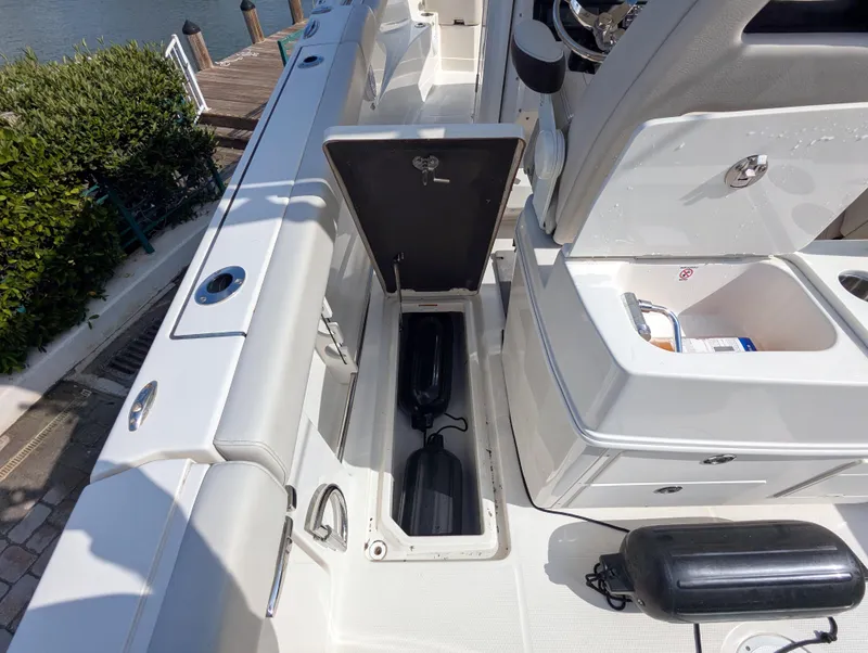 Slide: The Image of 2023 Sailfish 272 CC boat interior with open storage compartment and dock view. - 21