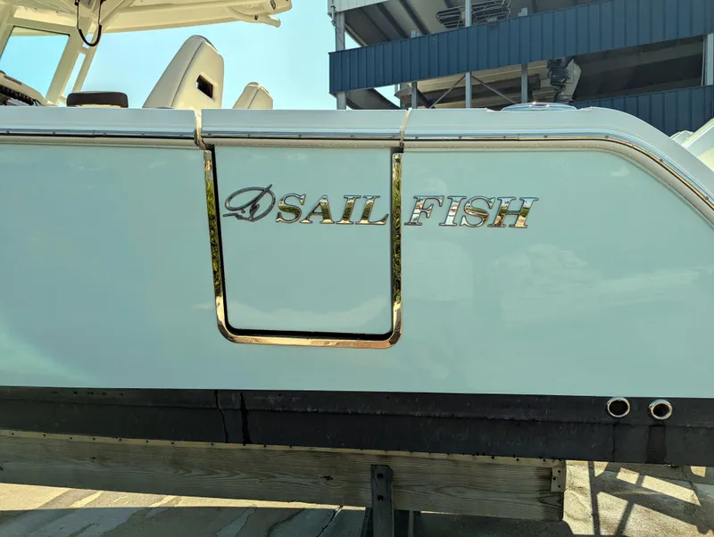 Slide: The Image of 2023 Sailfish 272 CC boat, side view with logo, docked under a blue structure. - 24