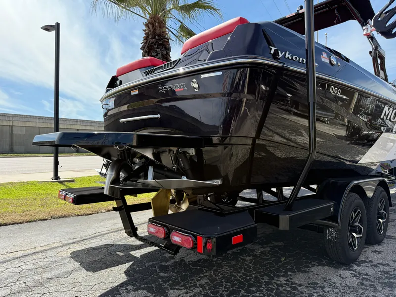 Slide: The Image of 2025 Moomba Tykon boat on trailer, rear view, black exterior, parked outdoors. - 18