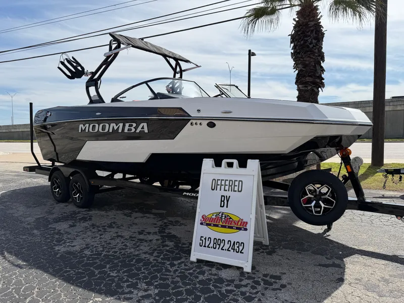 Slide: The Image of 2025 Moomba Tykon boat on trailer, displayed outdoors with sales sign. - 2