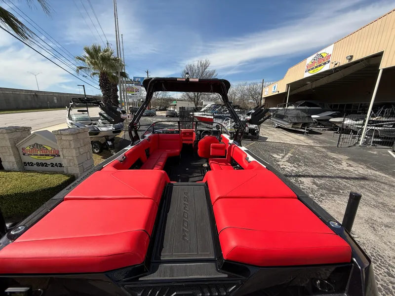 Slide: The Image of 2025 Moomba Tykon boat with vibrant red seating, parked outdoors under a clear sky. - 22