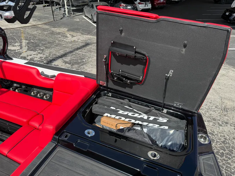 Slide: The Image of 2025 Moomba Tykon boat with open storage compartment and red seating. - 23